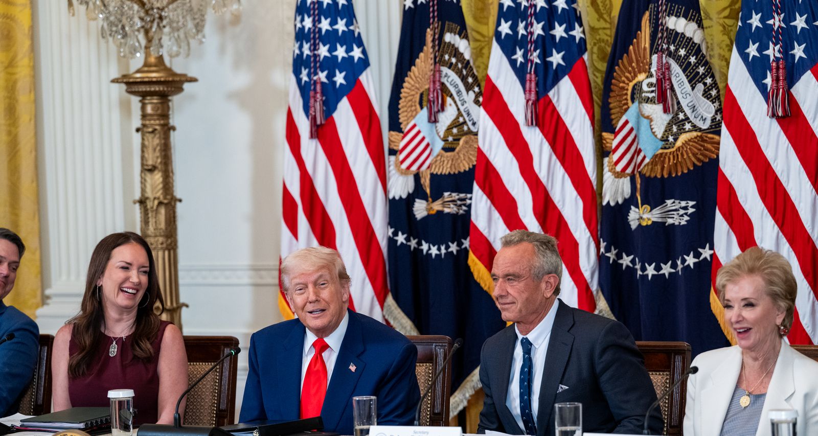 President Trump and Secretary Kennedy seated at a table in the East Room with members of the MAHA Commission